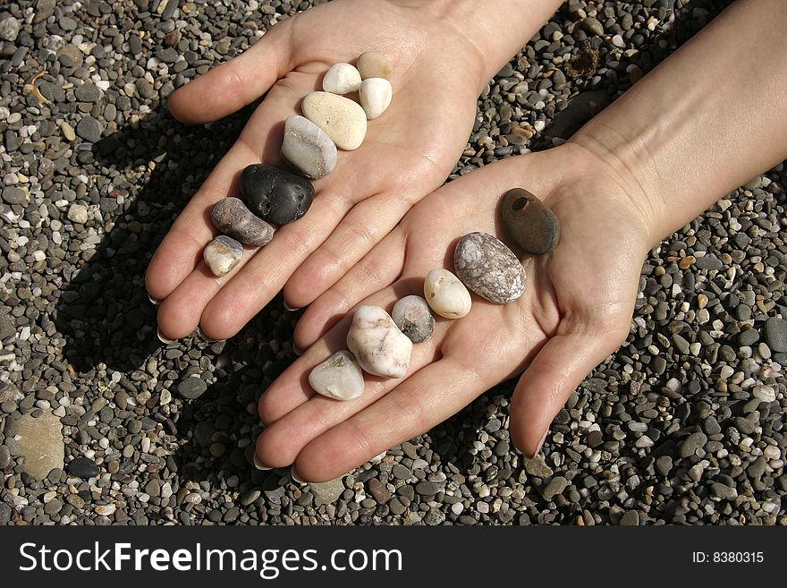 Hand with stone on summer sun beach
