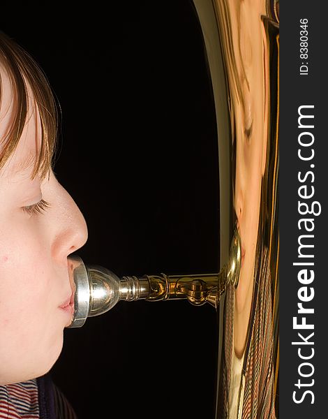 Girl playing on the euphonium with her face reflected on the shiny brass. Girl playing on the euphonium with her face reflected on the shiny brass