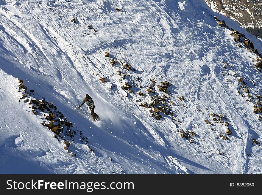 A female snowboarder descends a technical slope on a sunny day in Montana. A female snowboarder descends a technical slope on a sunny day in Montana.