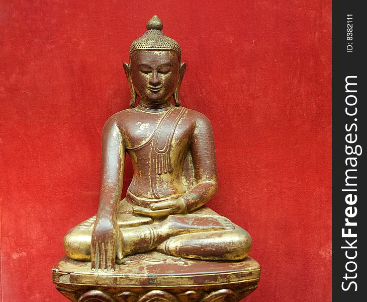 Sitting Buddha statue on red background