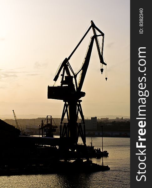 Dockyard crane next to the sea during sunset. Dockyard crane next to the sea during sunset