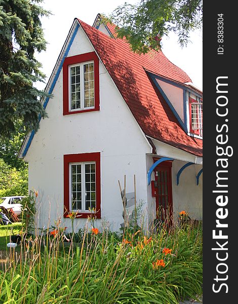 Side view of a white stucco cottage with a high red roof. Side view of a white stucco cottage with a high red roof