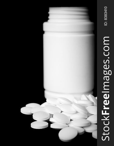Bottle with white pills on black background