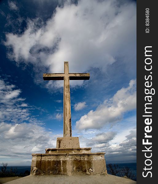 Cross made of stone on the top of the hill near the clouds pointing to the heaven above. Cross made of stone on the top of the hill near the clouds pointing to the heaven above