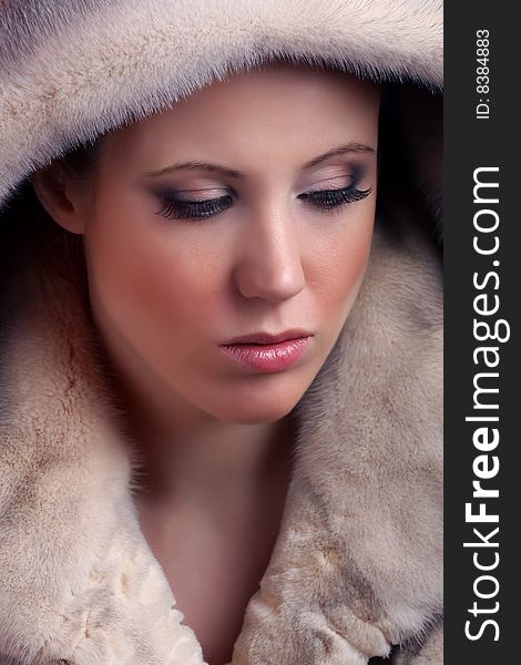 Portrait of attractive young woman wearing fur and looking away from camera