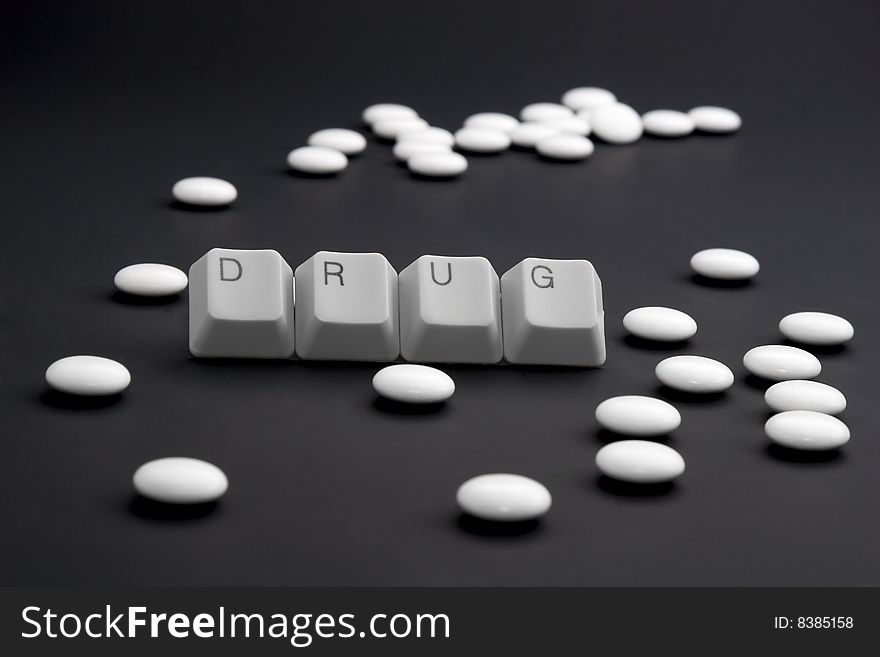 DRUG caption by keyboard keys and pile of pills on black. DRUG caption by keyboard keys and pile of pills on black