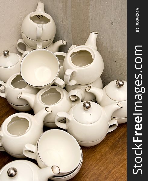 Pileup of white teapots on brown table