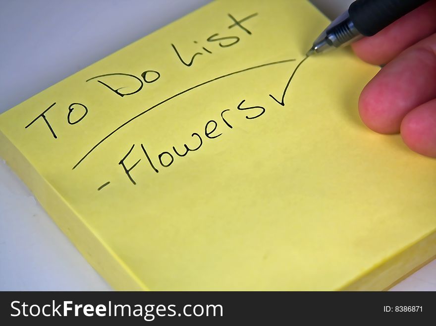 Yellow sticky note with someone writing flowers with a pen. Yellow sticky note with someone writing flowers with a pen