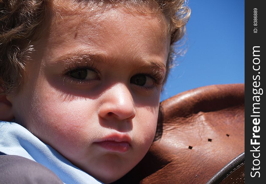 Close up of a small boys face resting against the leather hat. Close up of a small boys face resting against the leather hat.