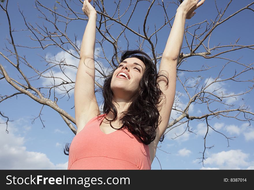 Woman with her arms extended with a bare tree in the background. Woman with her arms extended with a bare tree in the background