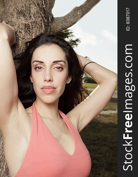 Beautiful young woman posing by a tree