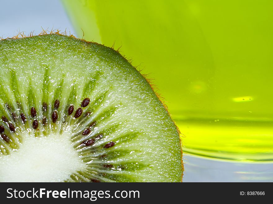 A kiwi in front of a wide mouthed glass filled with lime green water. A kiwi in front of a wide mouthed glass filled with lime green water.
