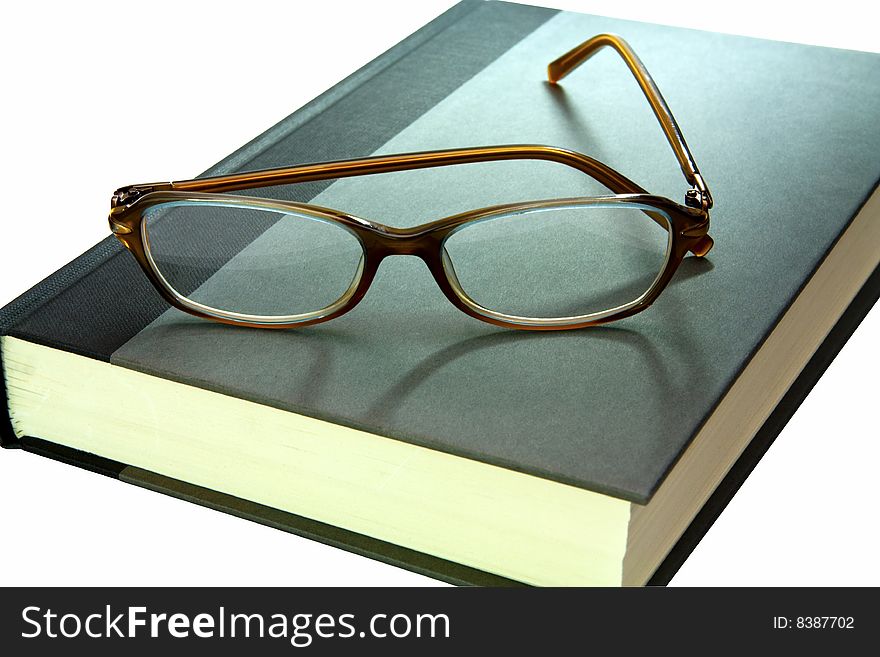 Hard back book with pair of reading glasses on top close up. Hard back book with pair of reading glasses on top close up