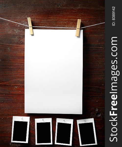 Photo paper attach to rope with clothes pins on wooden background