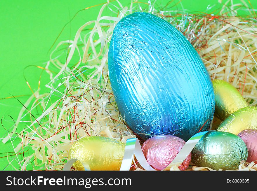 Assortment of chocolate Easter eggs wrapped in colorful paper in straw. Assortment of chocolate Easter eggs wrapped in colorful paper in straw