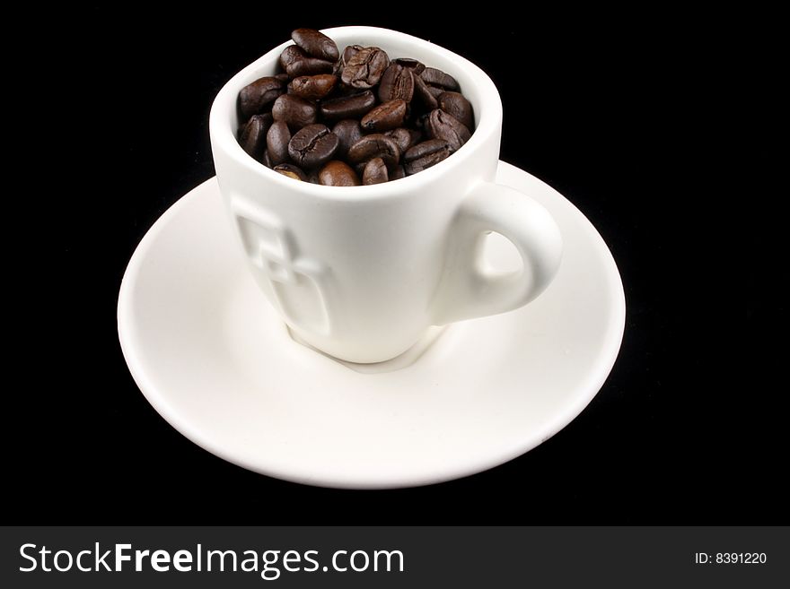 Coffee Cup with coffee beans in it on a Black Background. Coffee Cup with coffee beans in it on a Black Background