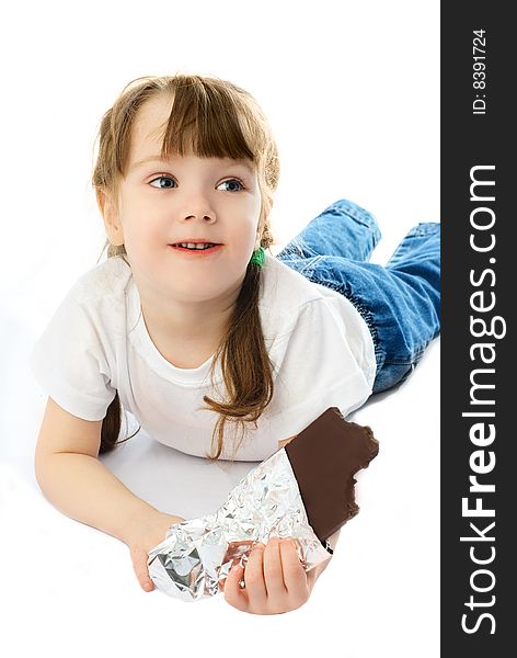 Portrait of a cute little girl eating chocolate on the floor