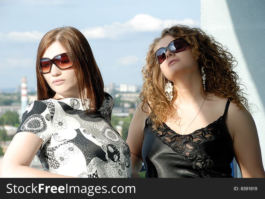 Two girls on the balcony watching the passers-by, relaxing. Two girls on the balcony watching the passers-by, relaxing