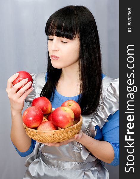 Beautiful girl holds in hands red apples on grey background