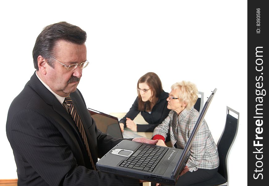 Businessman in office environment with laptop. Three people with focus on mature boss in front. Isolated over white. Businessman in office environment with laptop. Three people with focus on mature boss in front. Isolated over white.