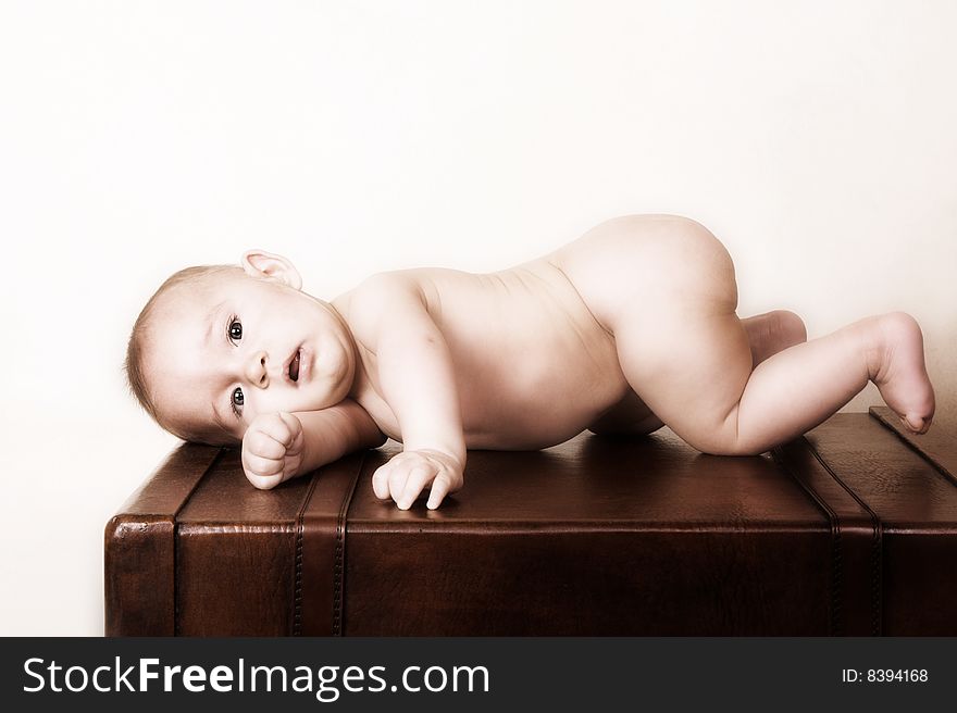 Young baby lying on his tummy on an old style suitcase