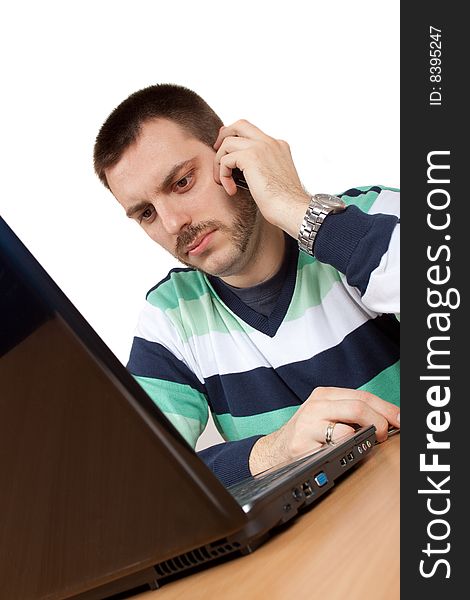 Man having a conversation on mobile phone in front of his notebook. Man having a conversation on mobile phone in front of his notebook