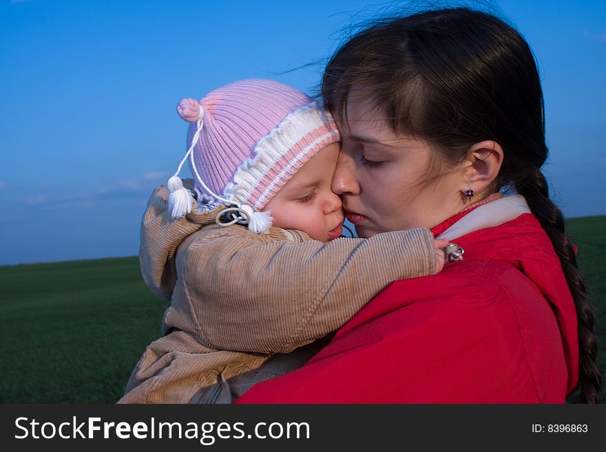 Little baby with mom on green grass and blue sky background