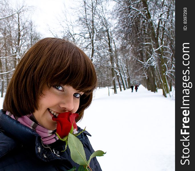 Young woman with rose and shiny smile in winter day