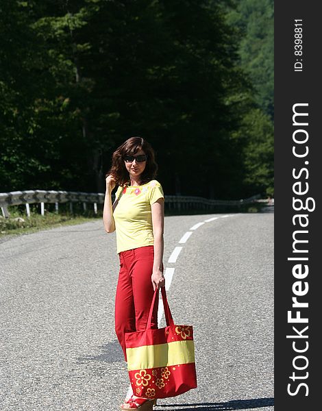 The girl is on road. She has red trousers and a yellow vest. The girl is on road. She has red trousers and a yellow vest.