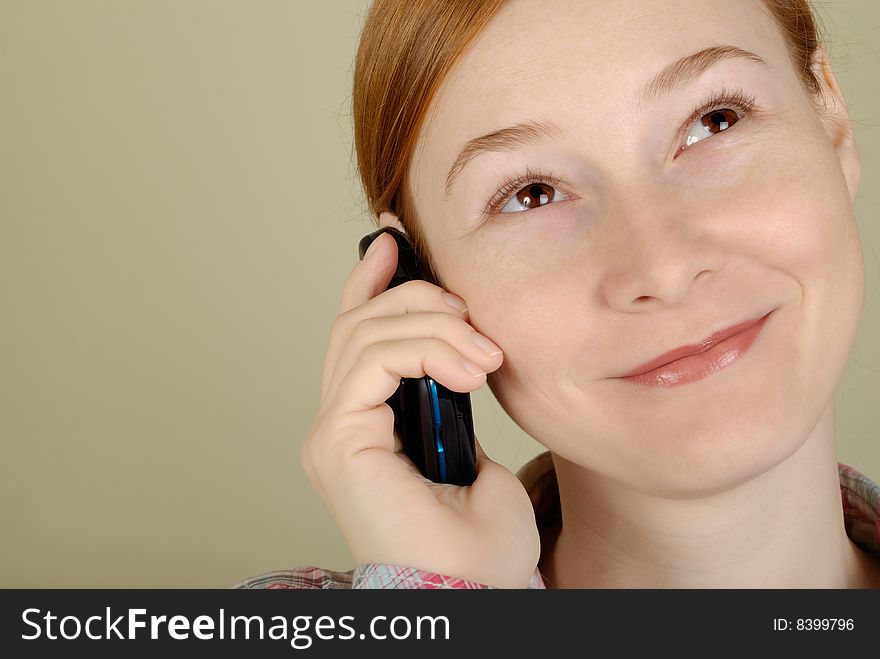 Redhead young woman speaks on the mobile phone with copy space