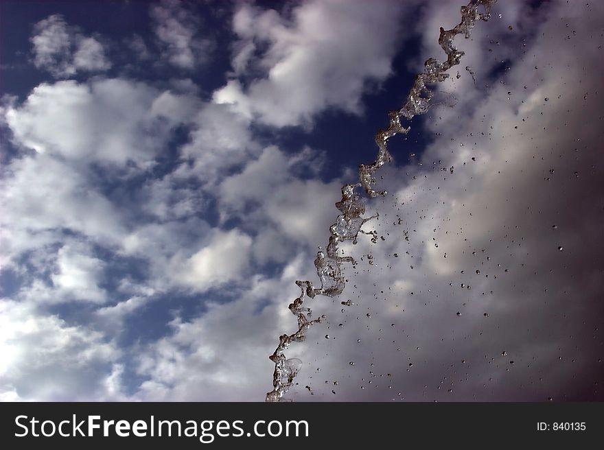 Water shot into the air, contrast against blue sky with clouds. Water shot into the air, contrast against blue sky with clouds