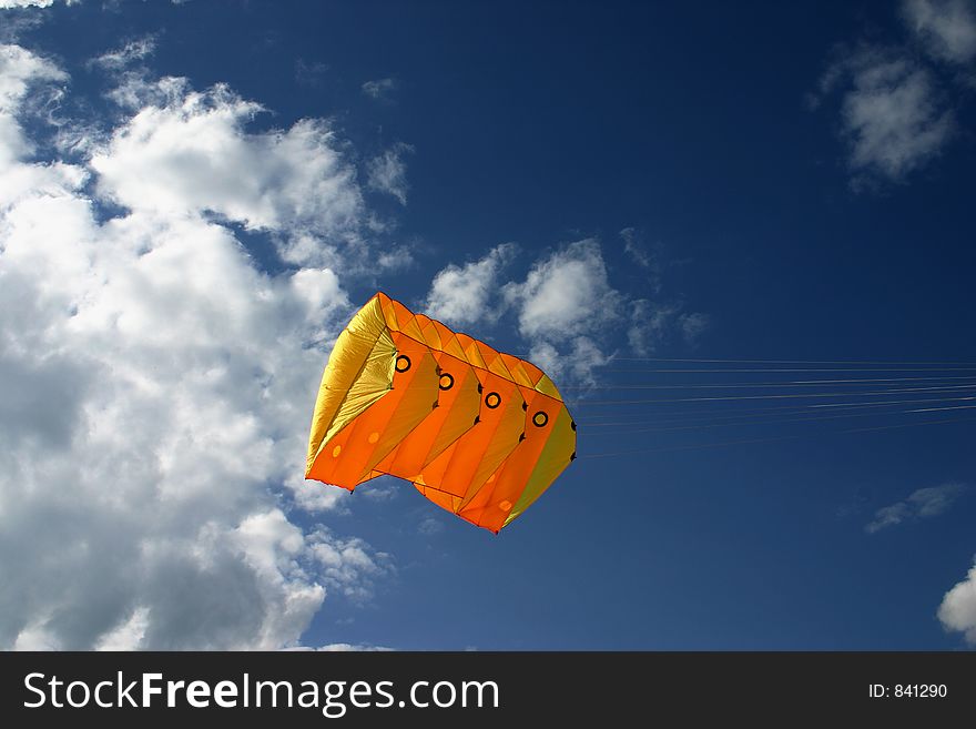 Orange kite next to the clouds