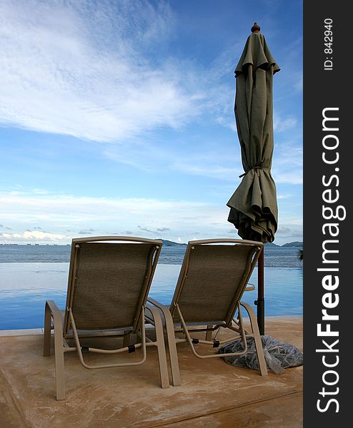 Some chairs on a beach front pool waiting for you to sit on them. Some chairs on a beach front pool waiting for you to sit on them