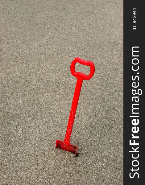 A red shovel on brownish sand with space over to write or add text. A red shovel on brownish sand with space over to write or add text.
