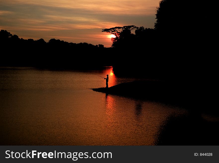A Man Fishing During The Sunset. A Man Fishing During The Sunset