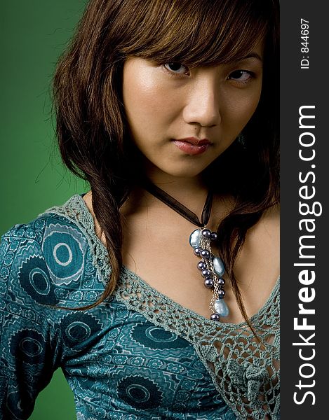 A beautiful young asian woman in a blue dress on green background. A beautiful young asian woman in a blue dress on green background