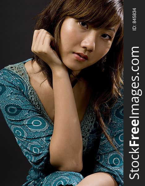 A beautiful young asian woman sitting against black background. A beautiful young asian woman sitting against black background