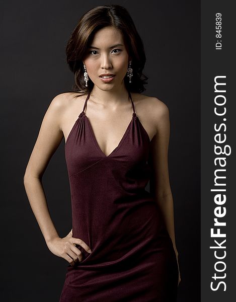 A beautiful asian woman in a velvet evening dress on black background. A beautiful asian woman in a velvet evening dress on black background