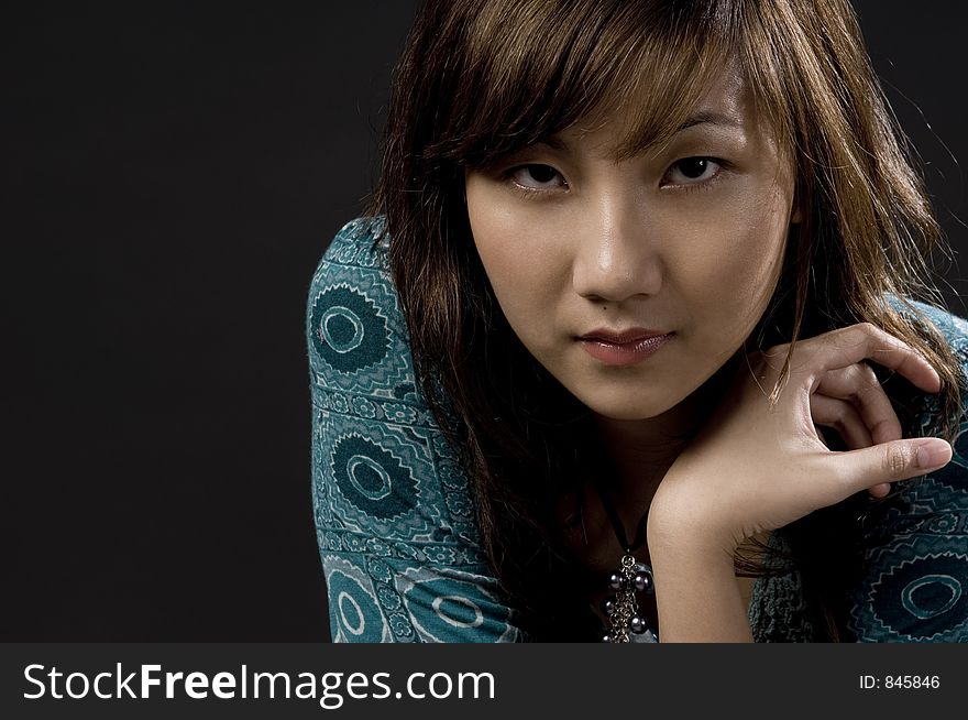 A pale beautiful asian woman in blue dress on black. A pale beautiful asian woman in blue dress on black