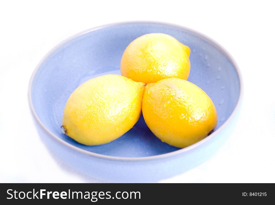 A blue bowl of fresh lemons on white. A blue bowl of fresh lemons on white