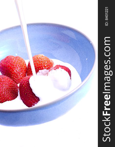 Cream being poured on to a bowl of fresh strawberries. Cream being poured on to a bowl of fresh strawberries