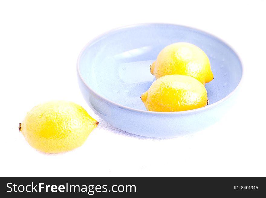 Fresh lemons in a blue bowl on white. Fresh lemons in a blue bowl on white