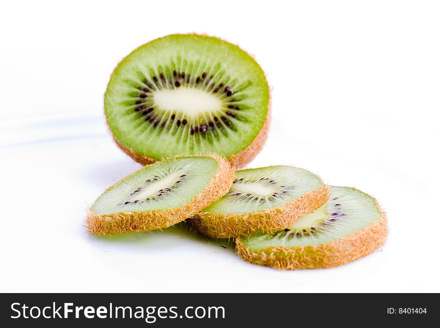 A halved kiwi fruit with slices on white. A halved kiwi fruit with slices on white