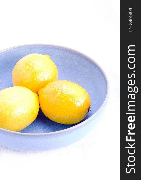 A group of fresh lemons in a blue bowl on white. A group of fresh lemons in a blue bowl on white