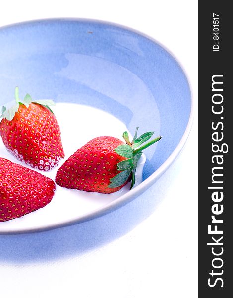 Three fresh leafed strawberries in a bowl of cream. Three fresh leafed strawberries in a bowl of cream