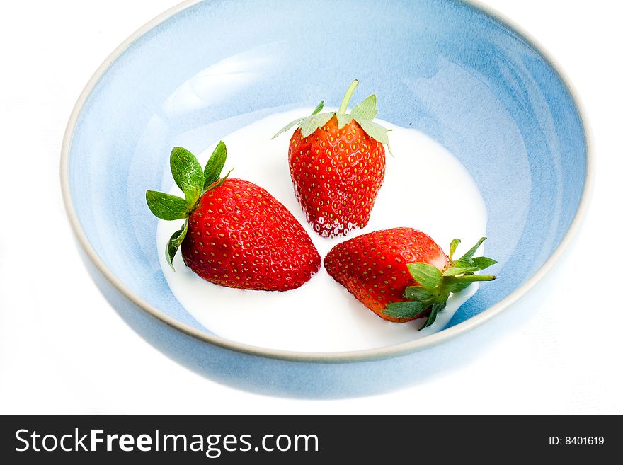 A blue bowl containing strawberries and cream. A blue bowl containing strawberries and cream