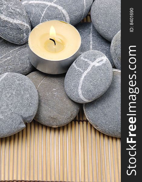 Zen stones and candle on a wooden bamboo set