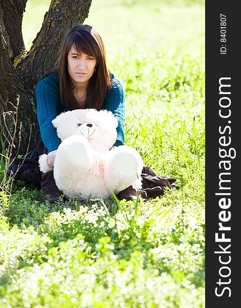 Young woman holding her teddy bear in a forest. Young woman holding her teddy bear in a forest.