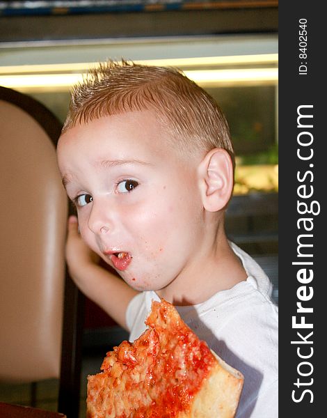 A young boy enjoying a slice of pizza. A young boy enjoying a slice of pizza.