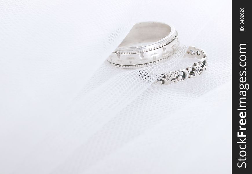 Closeup of wedding rings on a white veil